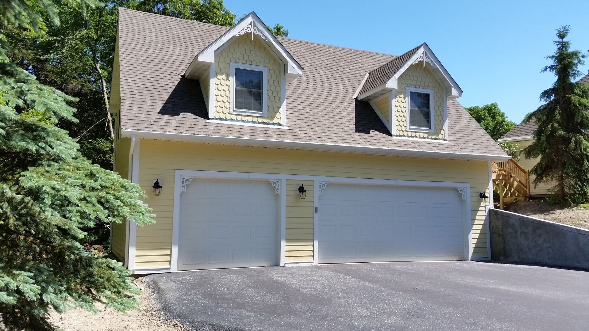 A yellow house with two garage doors and a brown roof