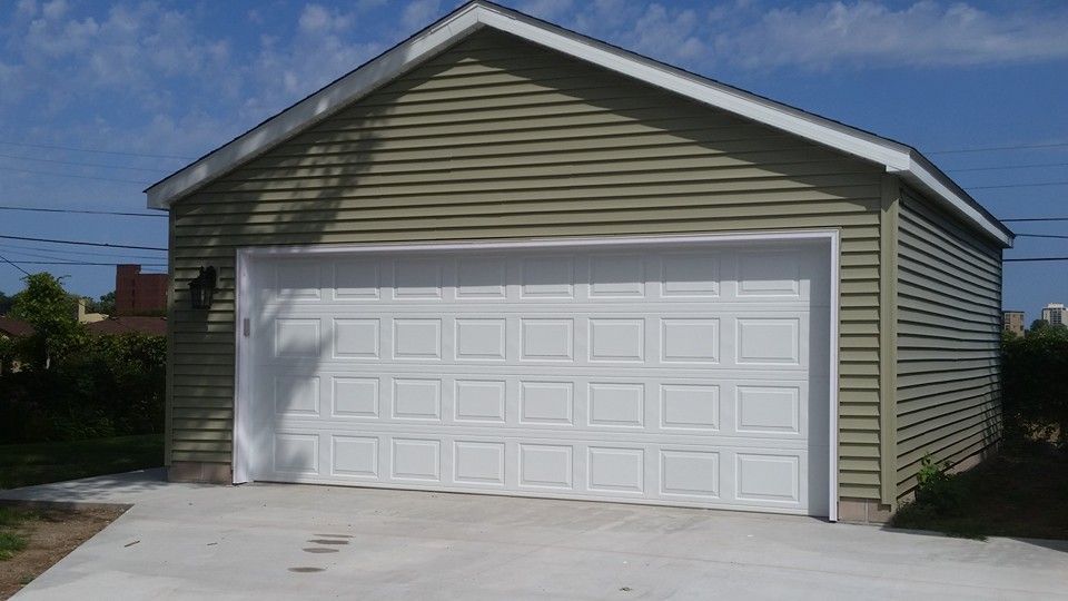 A garage with two white garage doors and a concrete driveway