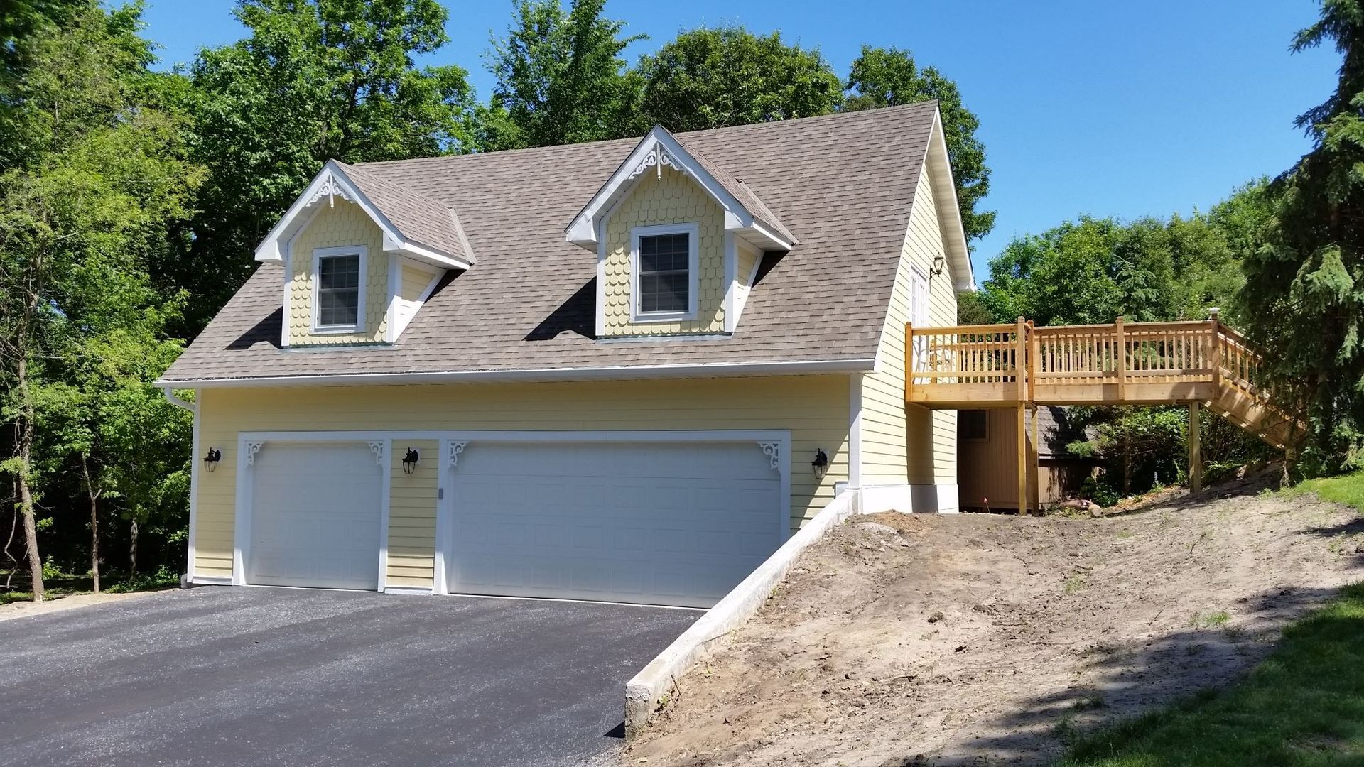 A house with two garage doors and a wooden deck