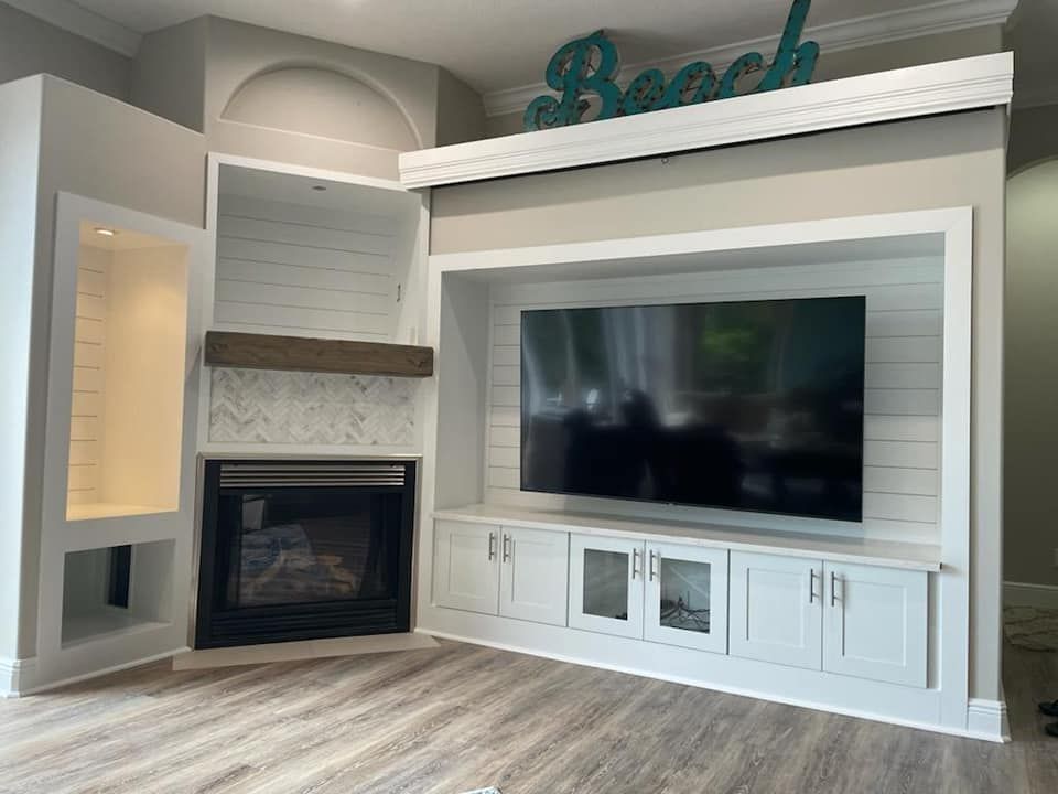 Built-in entertainment center with fireplace, TV, and storage cabinets. Light wood floors and a