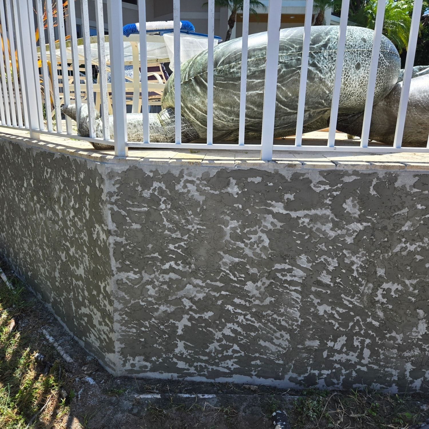 Concrete wall with peeling paint, white fence, large turtle sculpture.
