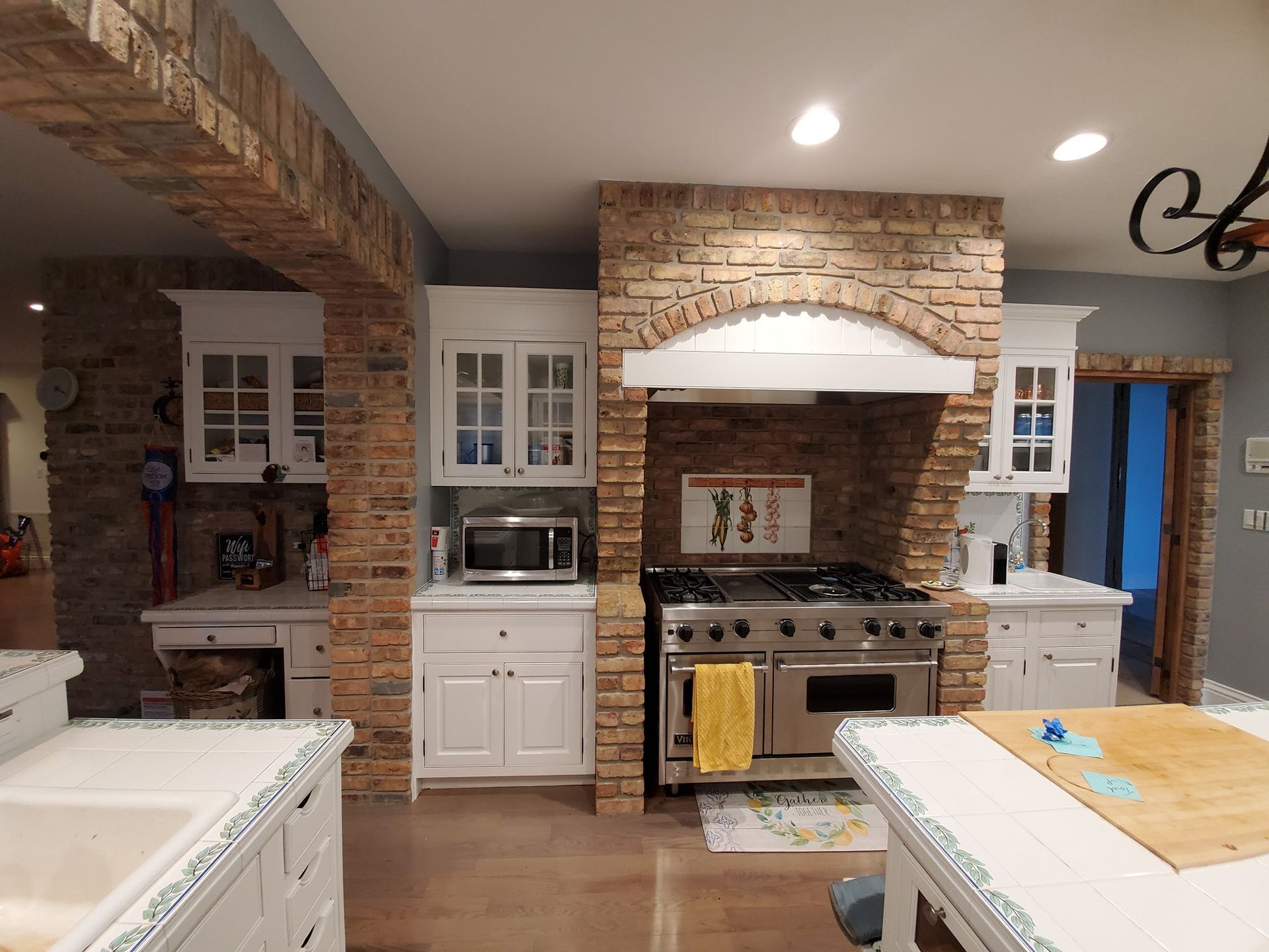 Kitchen with brick accents, white cabinets, stainless steel stove, and large island.