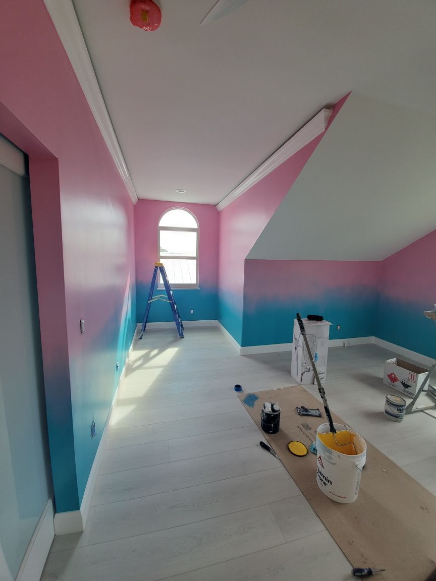 Room with walls painted in a pink-to-blue gradient, ladder, window, and painting supplies on the floor.