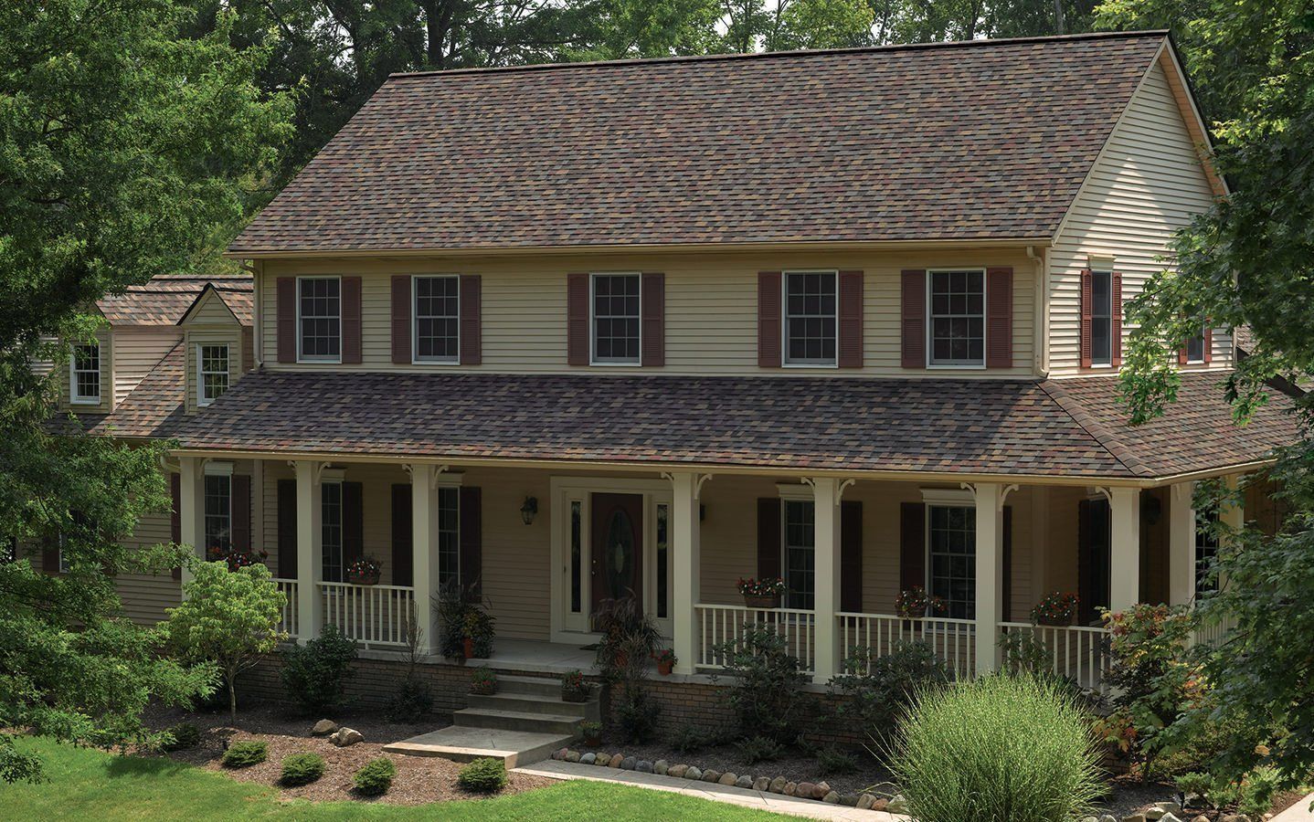 A large house with a large porch is surrounded by trees