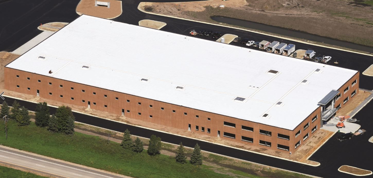 An aerial view of a large brick building with a white roof