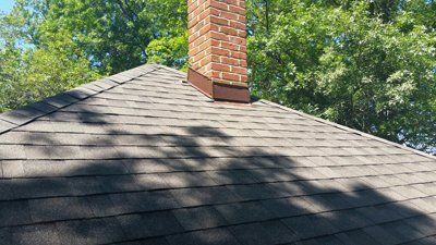 A roof with a chimney on top of it and trees in the background.