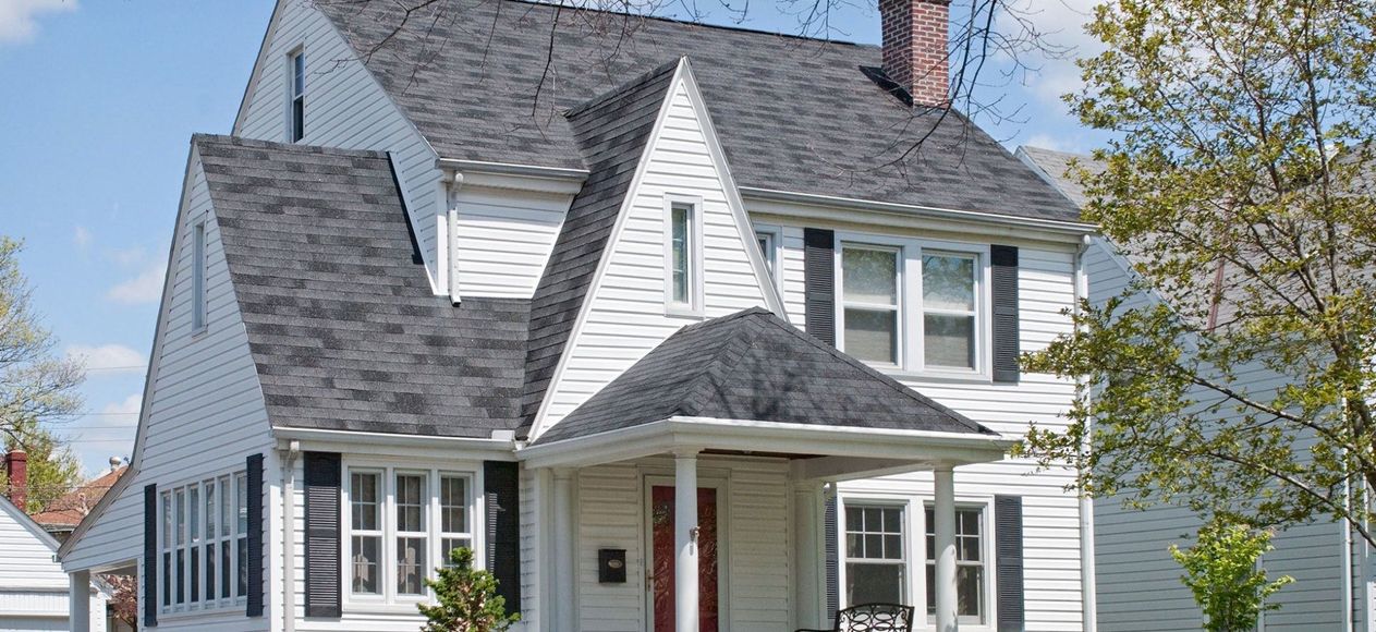 A white house with a gray roof and black shutters