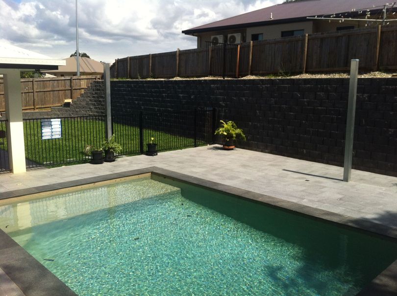 Natural stone paving with block retaining wall and new pool fencing