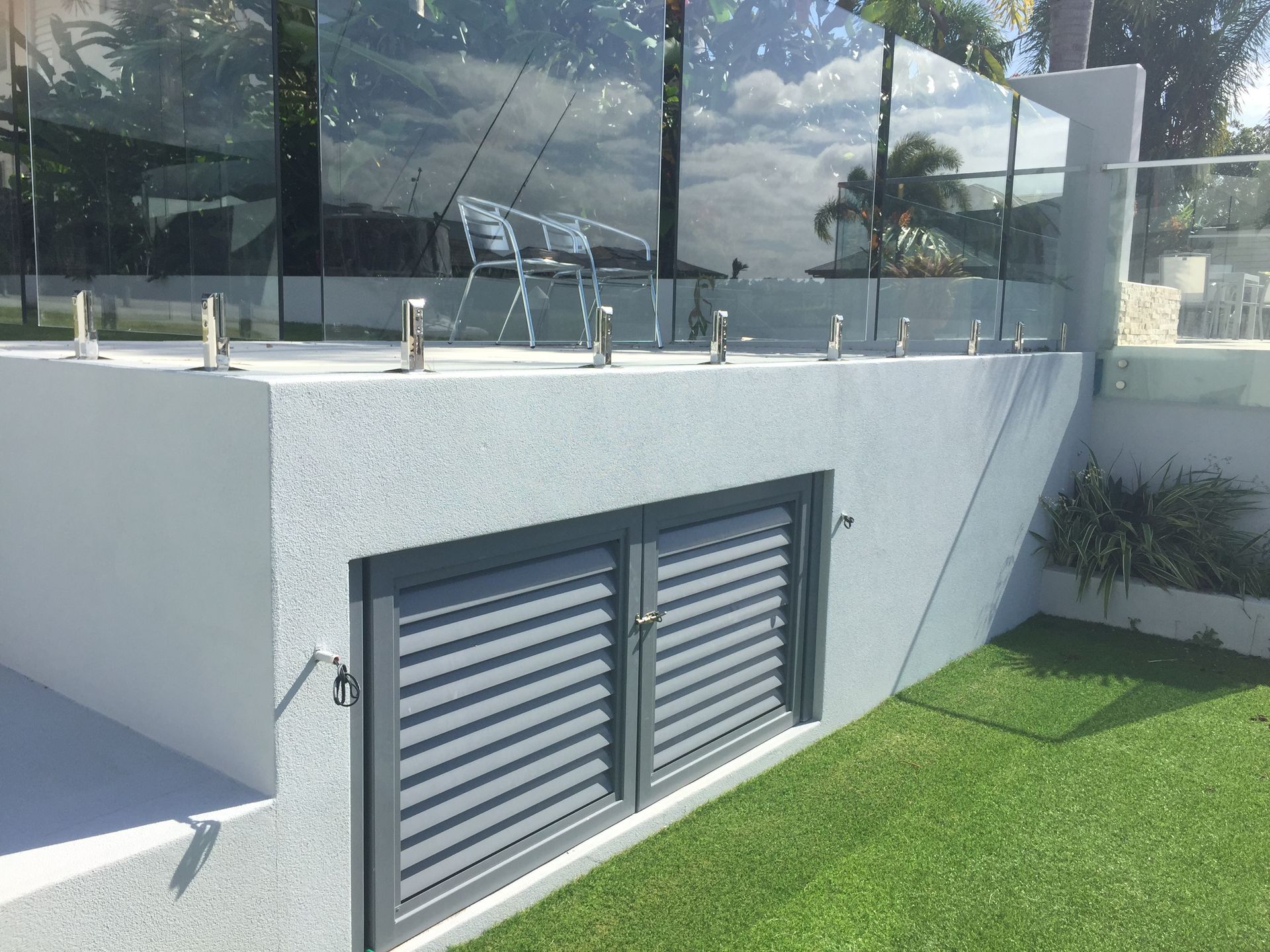 Modern white building exterior with a gray louvered vent and green lawn in front