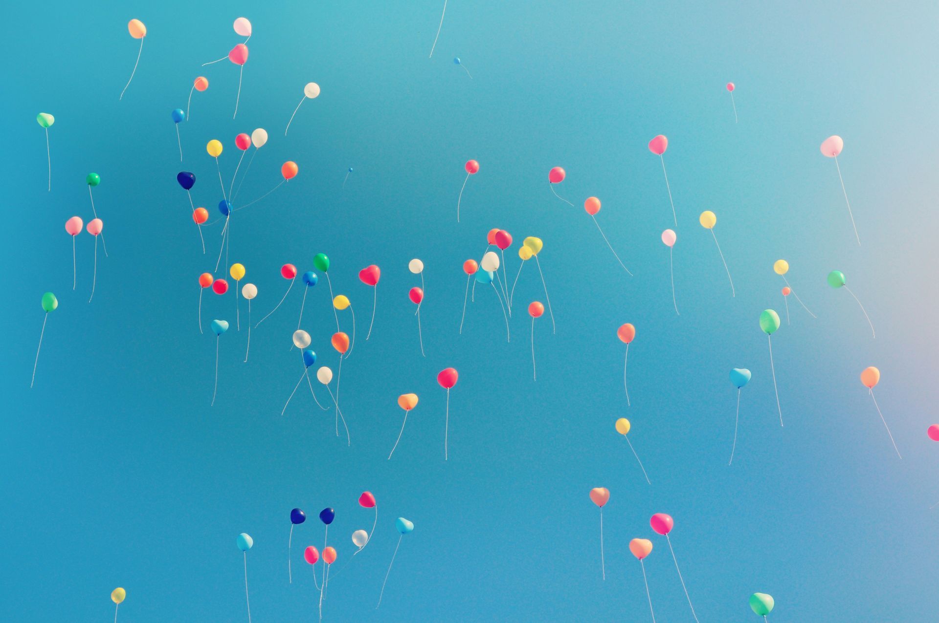 A bunch of colorful balloons are flying in the sky.