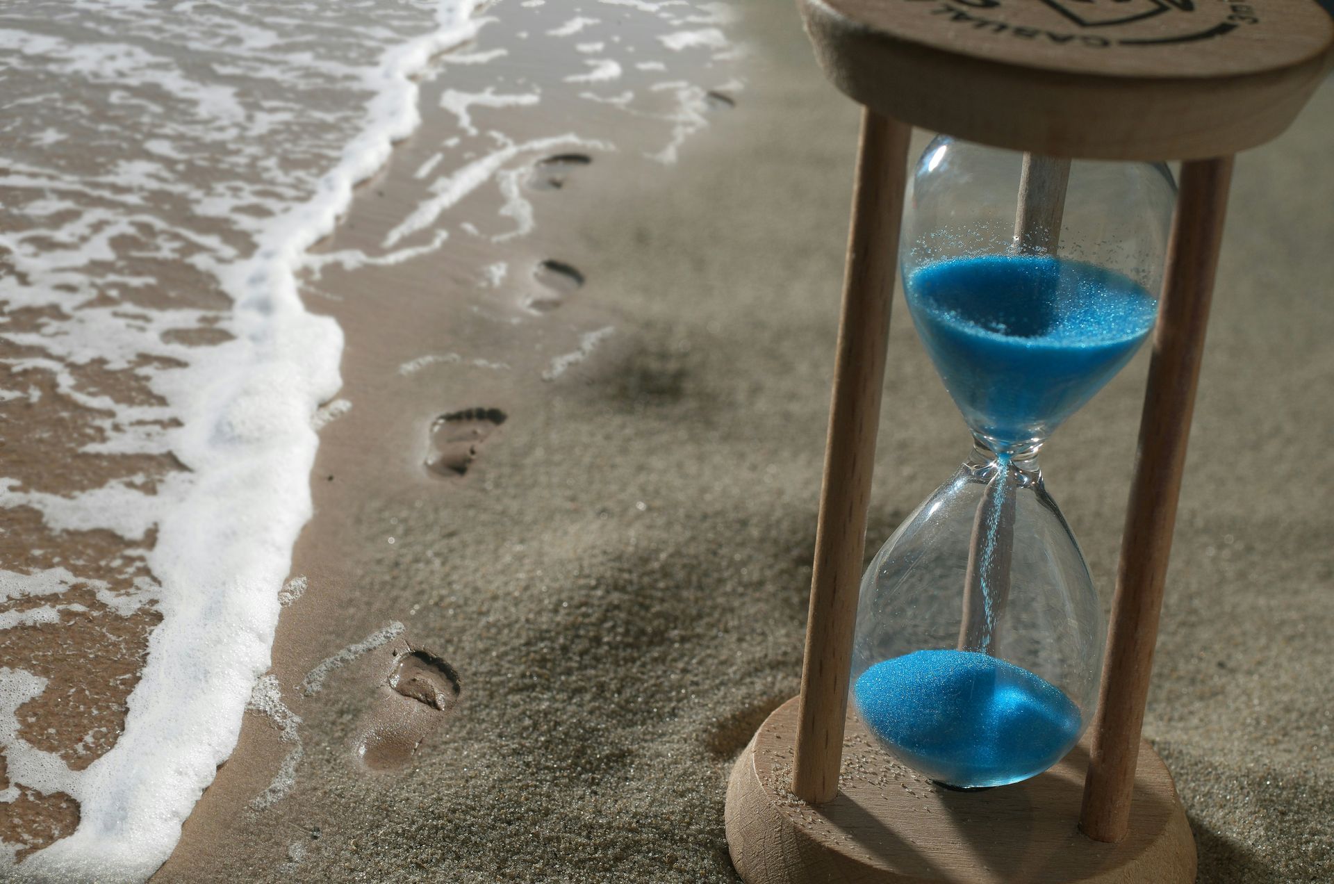 A hourglass is sitting on a sandy beach near the ocean