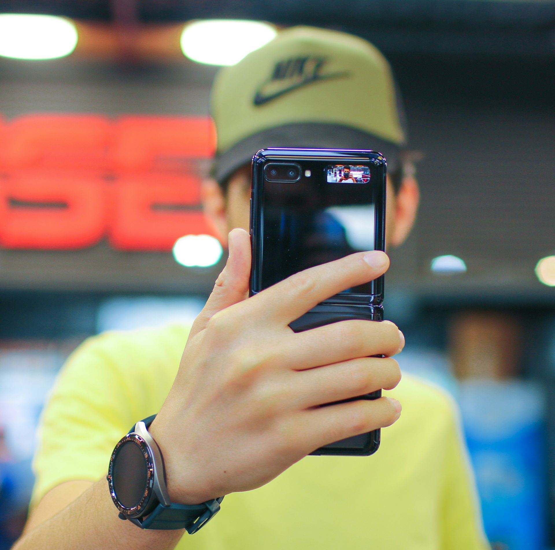 A man wearing a nike hat is taking a picture with his phone