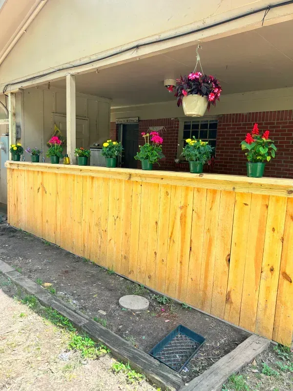 A wooden fence with flowers in pots on it