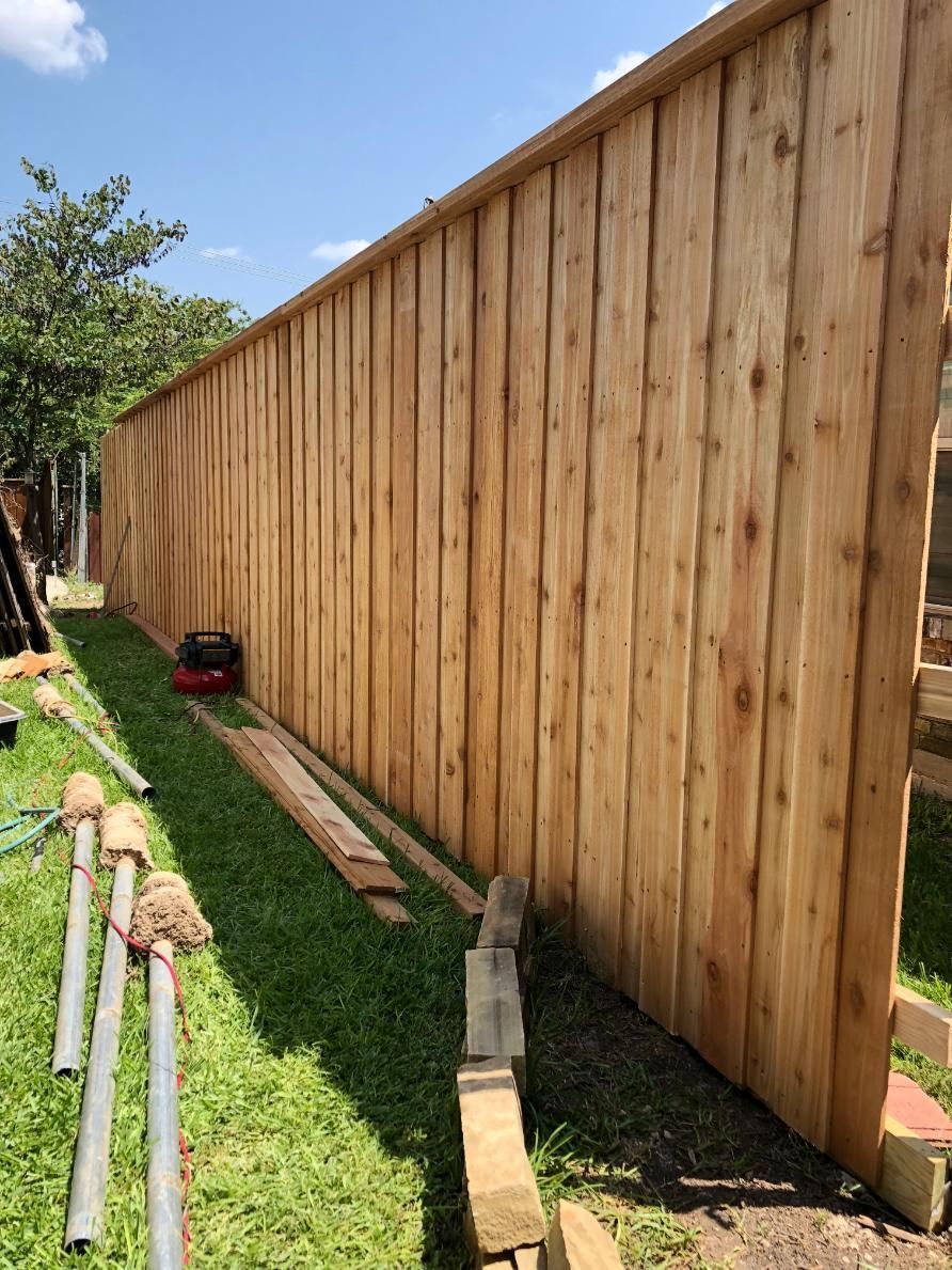 A wooden fence is being built in a backyard.