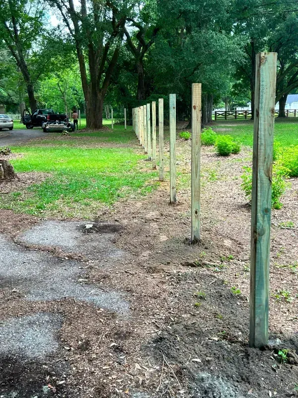 A wooden fence is being built in the middle of a grassy field.