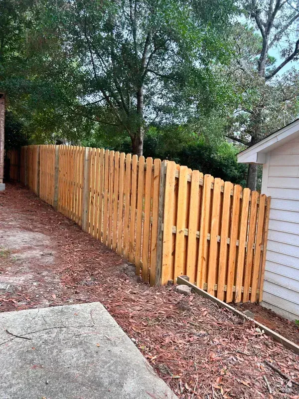 A wooden fence is in the backyard of a house.