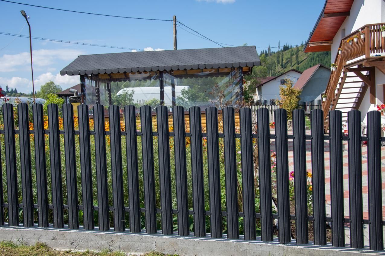 A black picket fence is in front of a house.