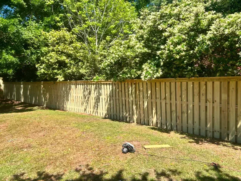 A wooden fence surrounds a lush green yard.