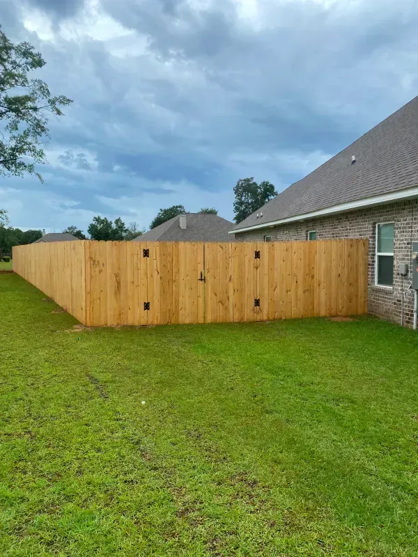 A wooden fence is in the backyard of a house.