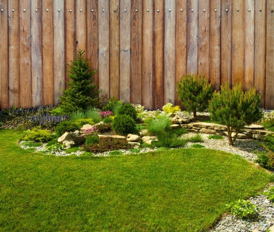 A wooden fence surrounds a lush green garden.