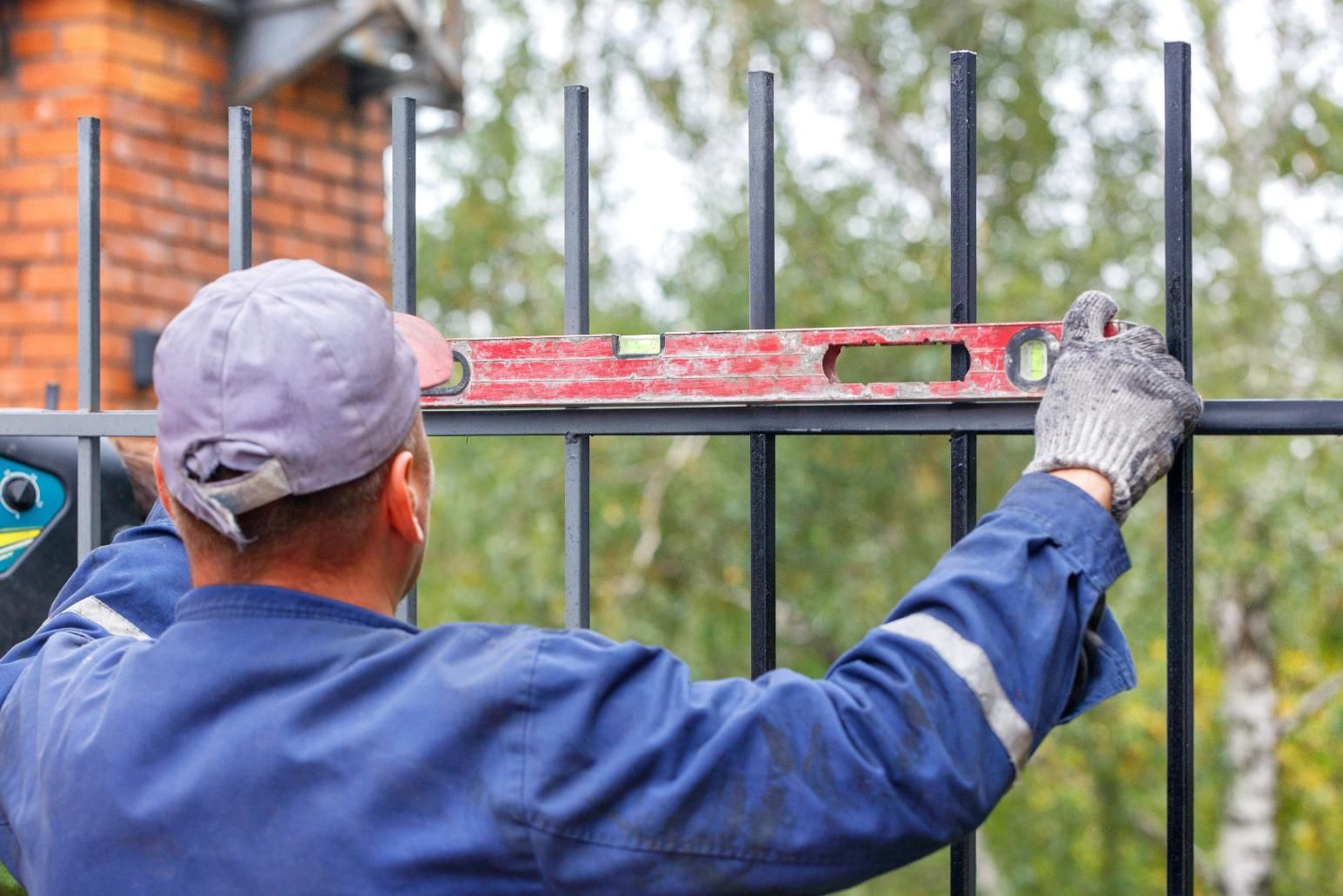 A man is measuring a metal fence with a level.