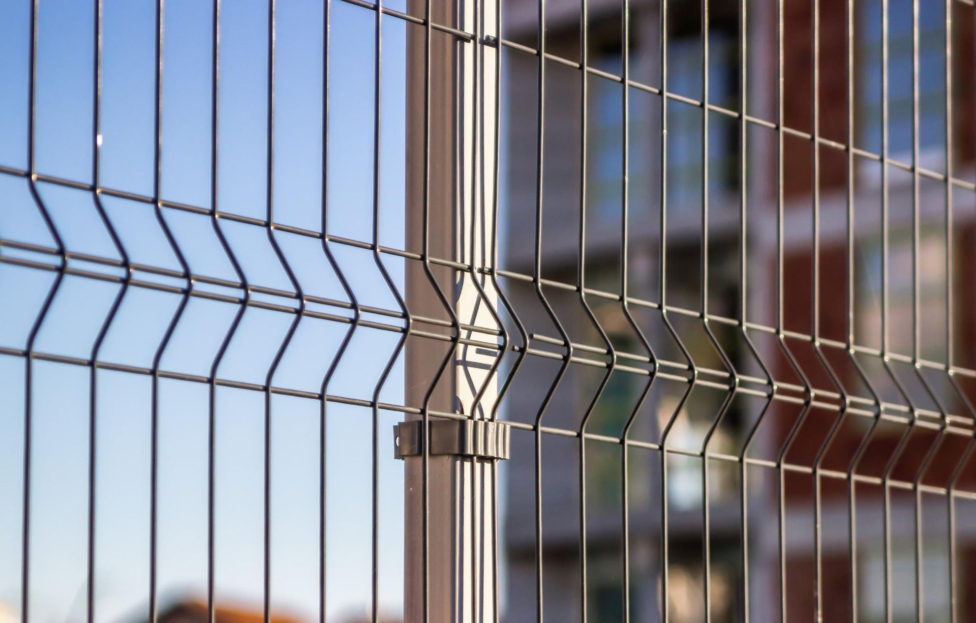 A close up of a wire fence with a building in the background.