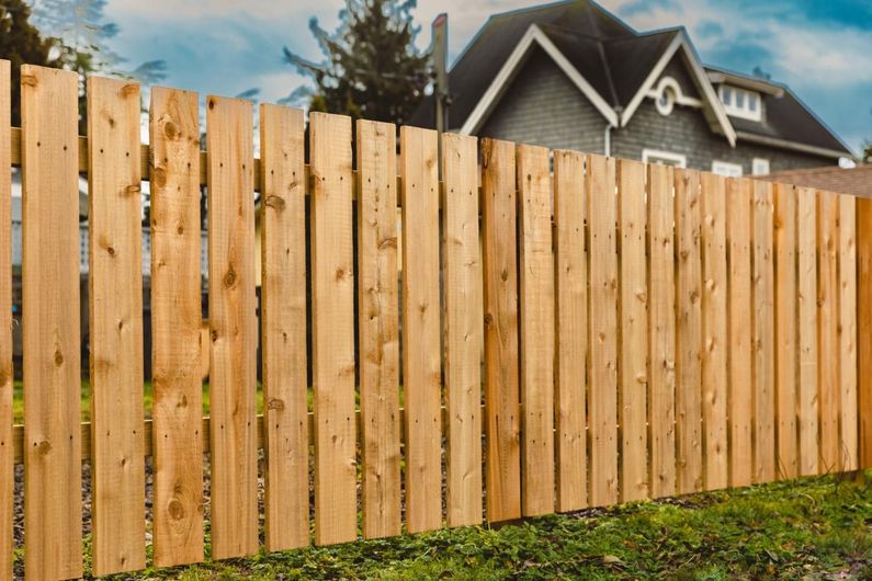 A wooden fence is in front of a house.