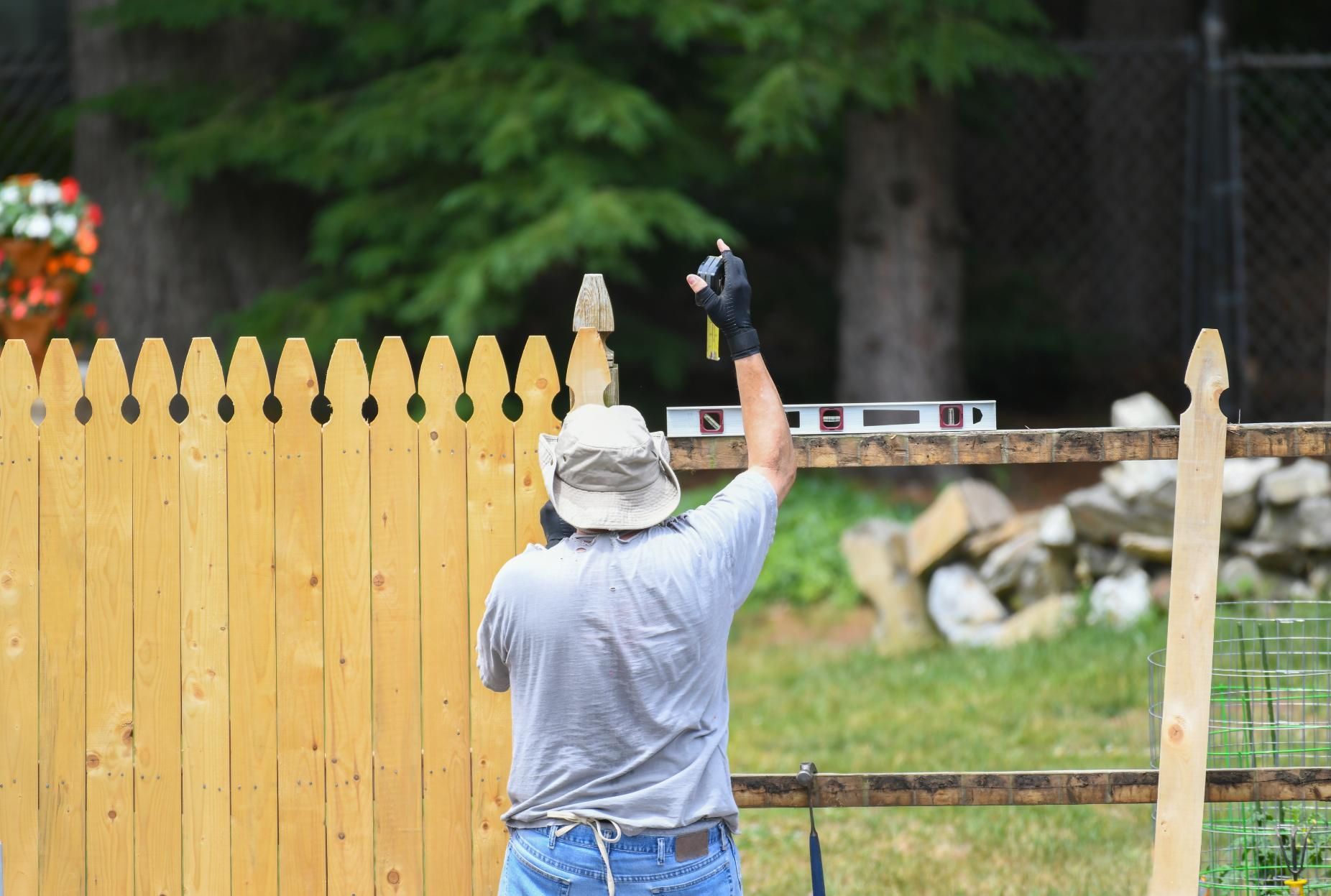 A man is leveling a wooden fence with a level.