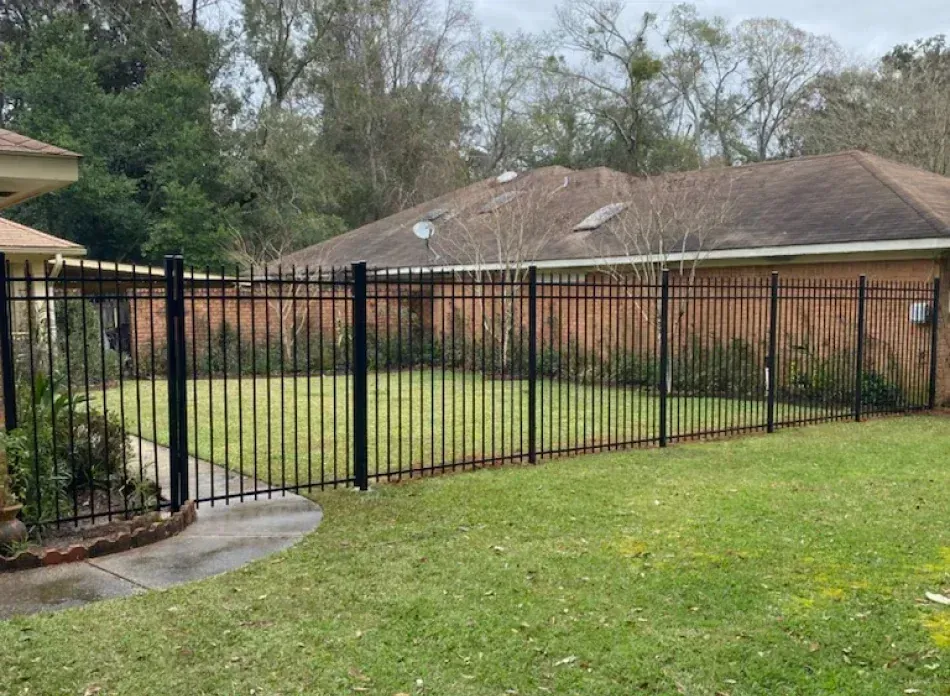 A black metal fence surrounds a lush green yard.