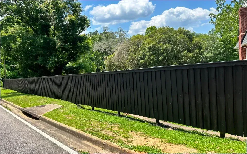 A long black fence is along the side of a road.