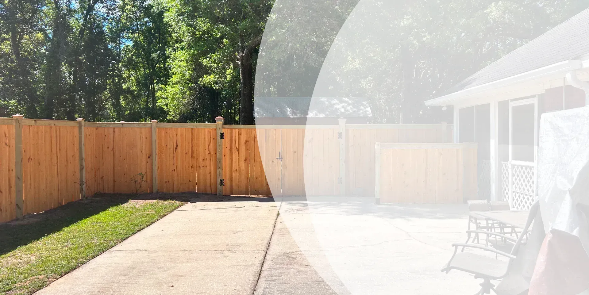 A wooden fence surrounds a driveway in front of a house.