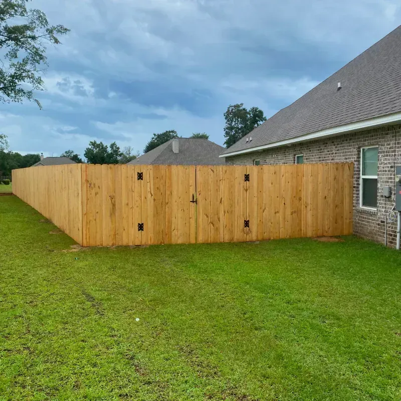 A wooden fence is in the backyard of a house.