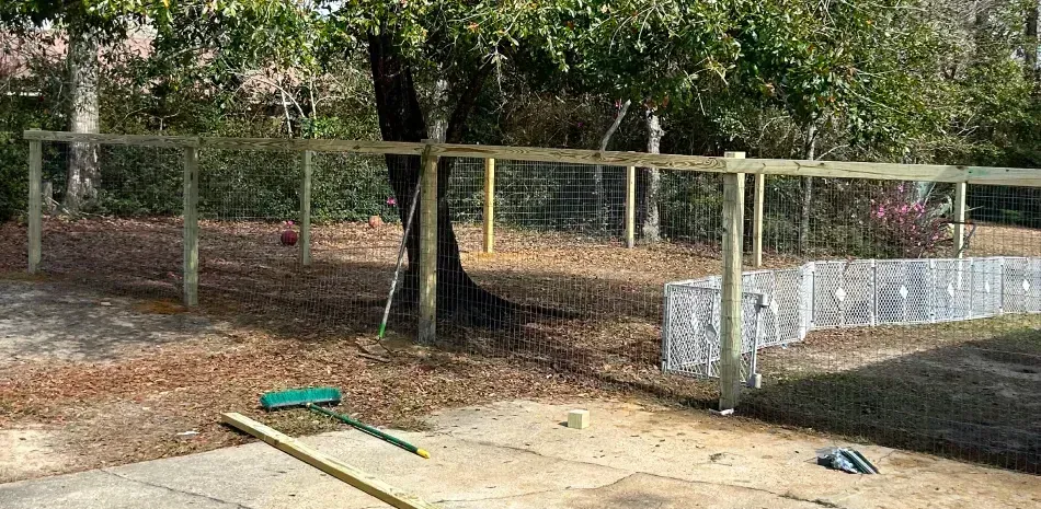 A wooden fence is being built in a backyard.