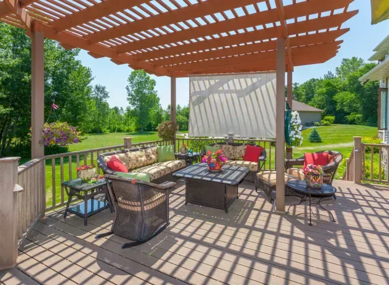 A deck with a pergola and patio furniture underneath it.