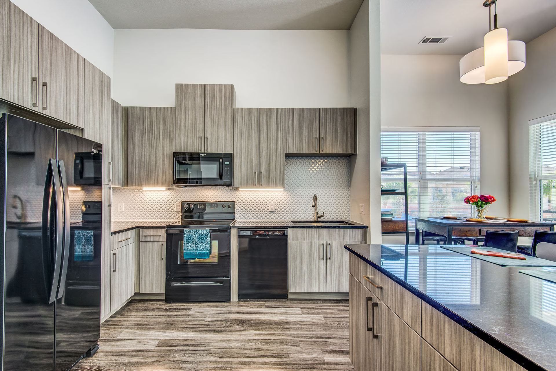 Modern kitchen with gray cabinets, black appliances, and a blue island countertop.