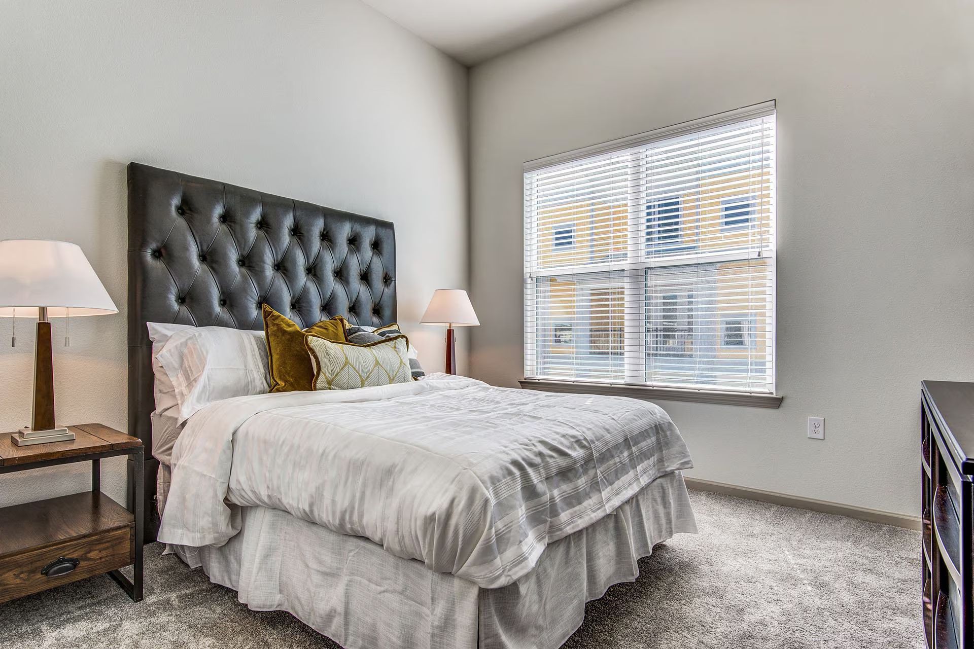 Bedroom with bed, tufted headboard, nightstands, and window with blinds.