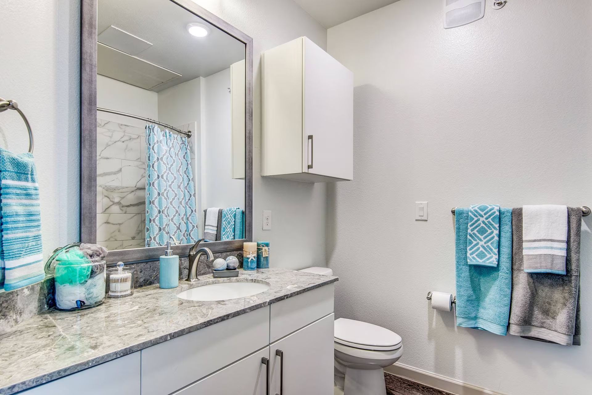 Bathroom with white cabinetry, granite countertop, and blue towels.