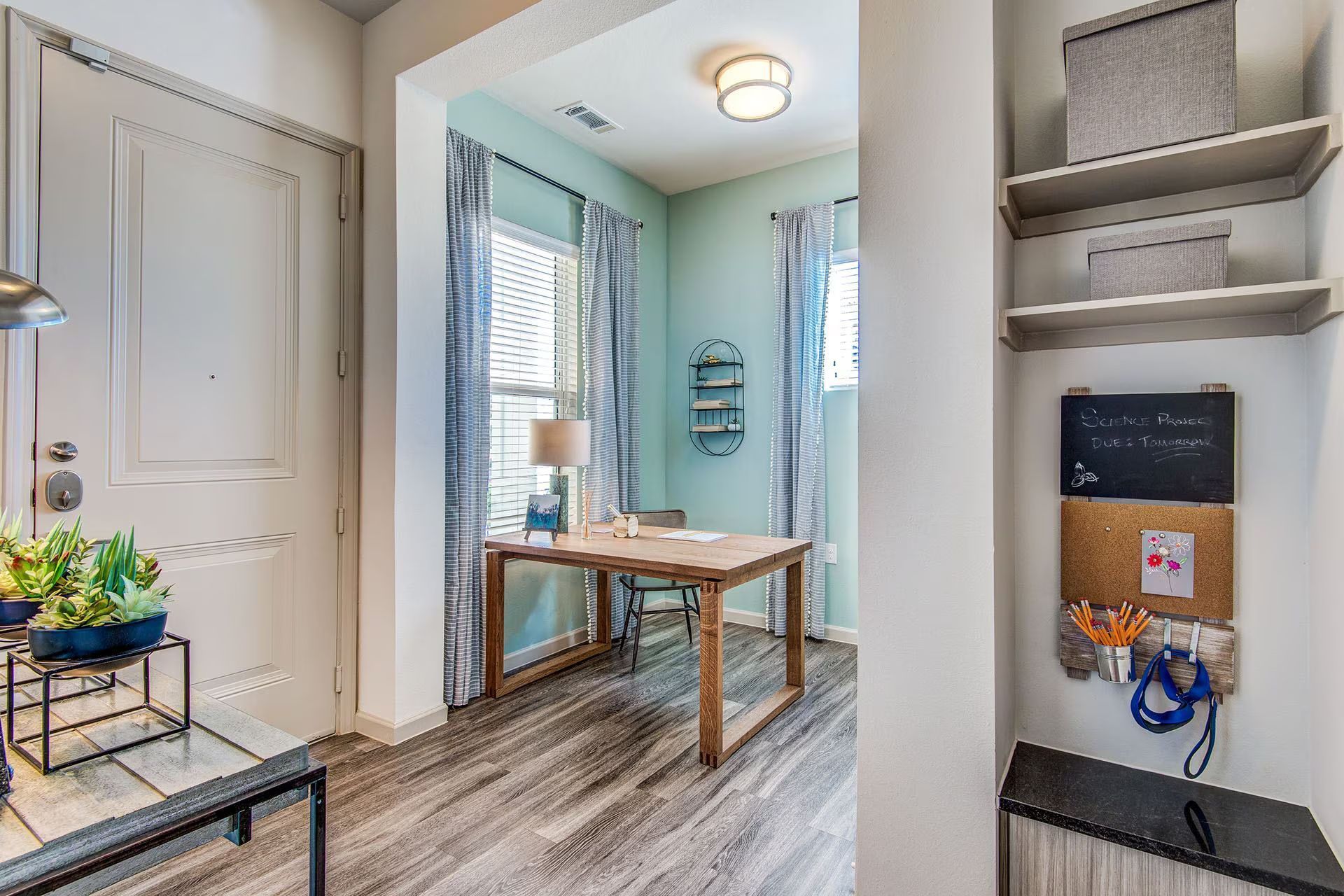 Entryway with a home office: a light-filled space with a desk, open shelving, and a door.