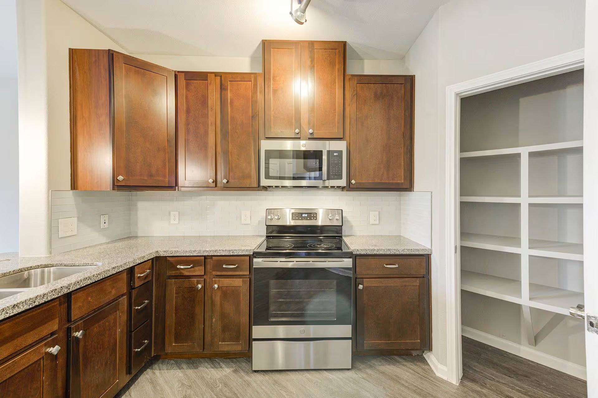 Kitchen with dark brown cabinets, stainless steel appliances, and pantry.