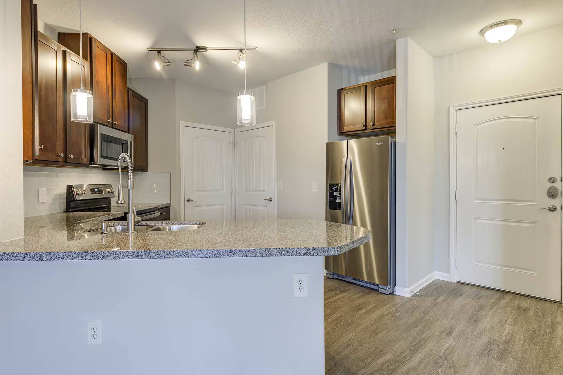 Kitchen with wood cabinets, granite countertops, stainless steel appliances, and wood-look flooring.