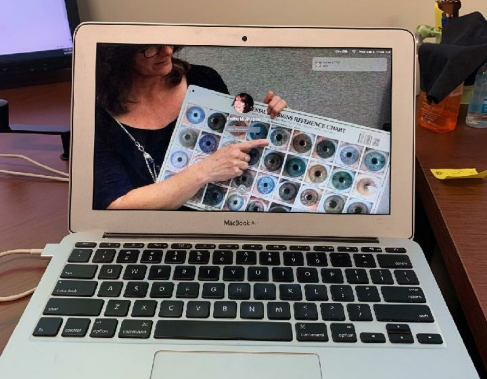 Laptop screen showing a woman pointing at an eye color chart.