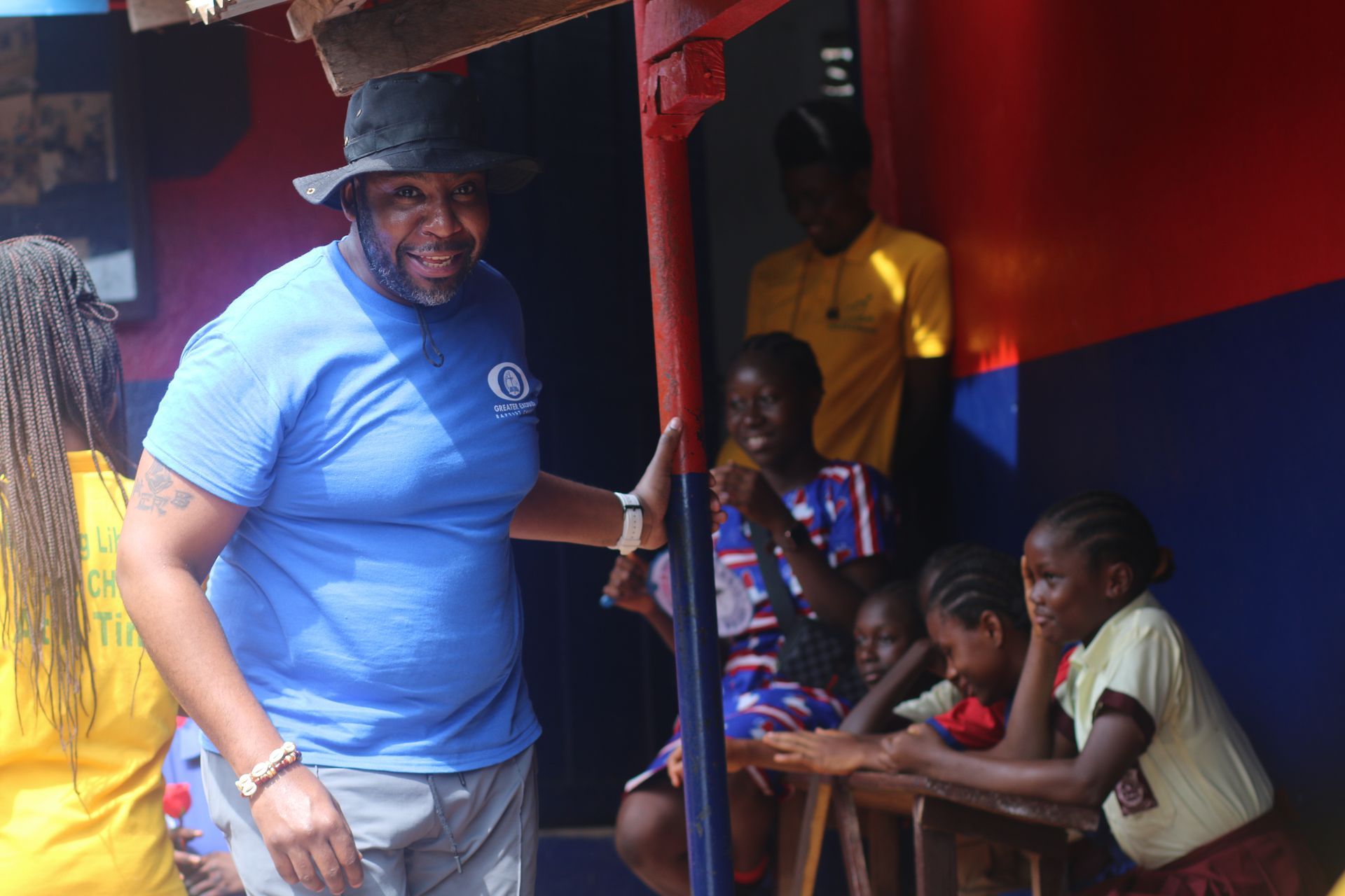 A man in a blue shirt is standing next to a group of children