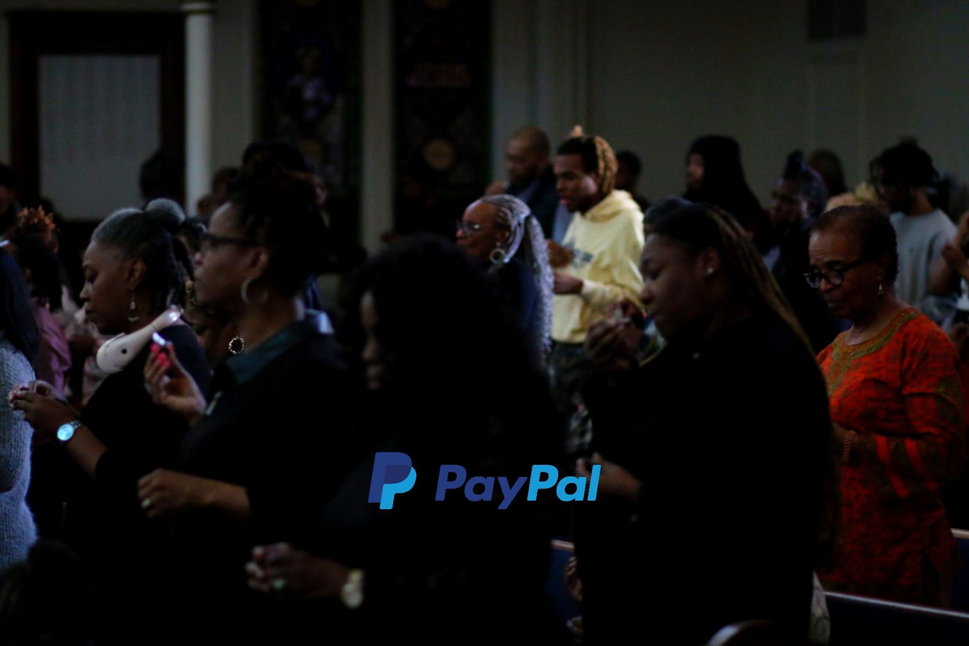 A group of people standing in a dark room with paypal written on the bottom