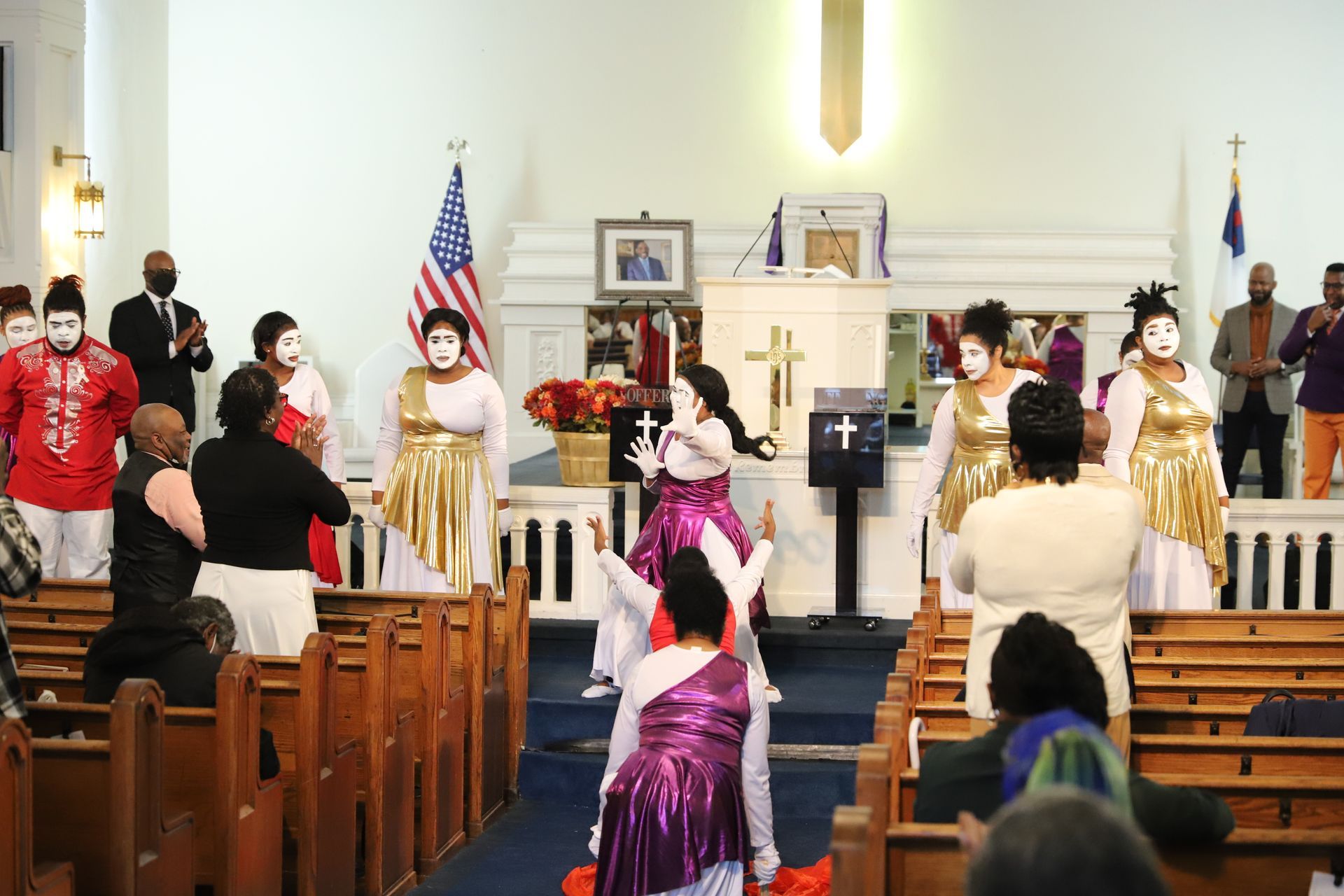 A group of people are dancing in a church while wearing masks.