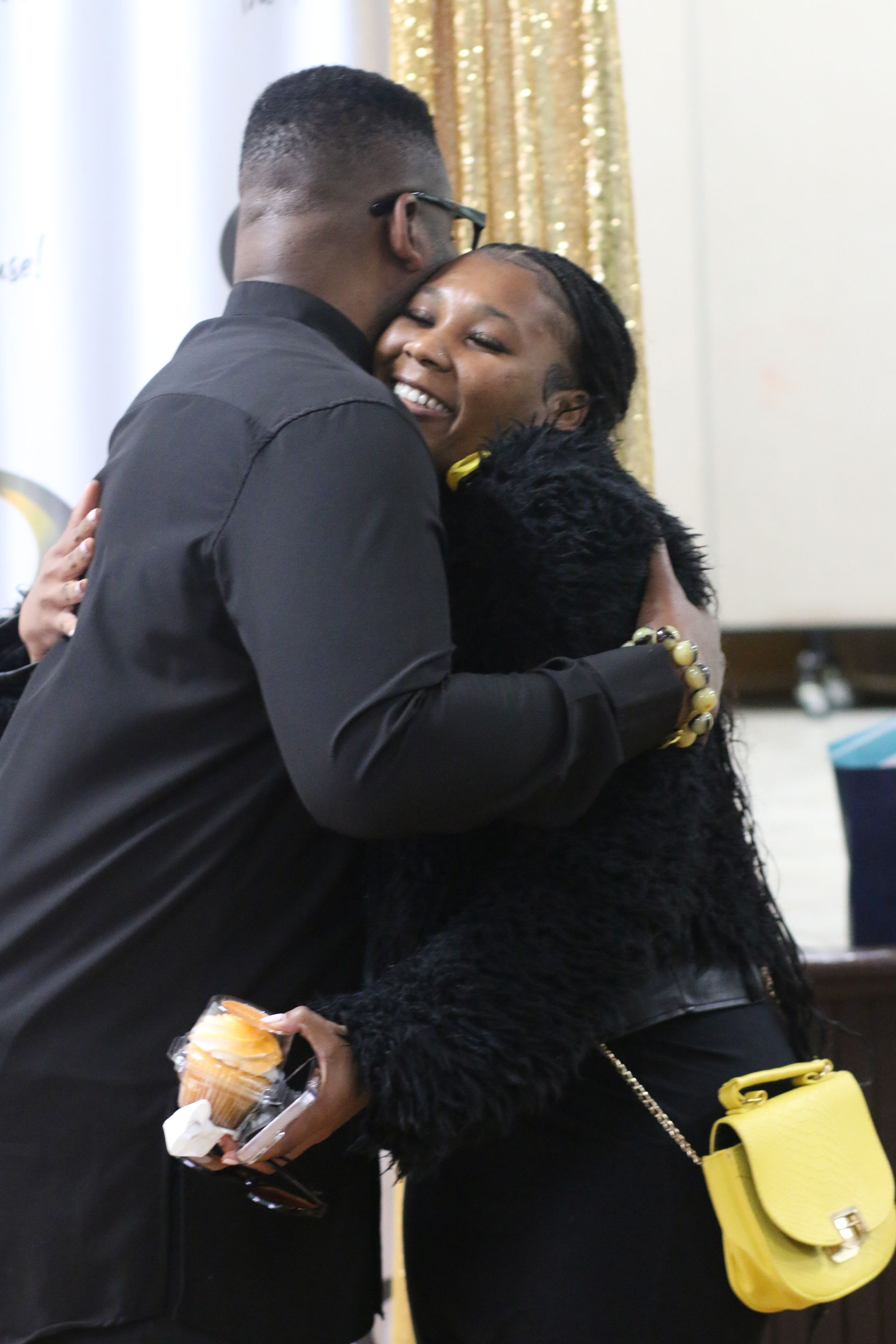 A man in a black shirt is hugging a woman in a black jacket.
