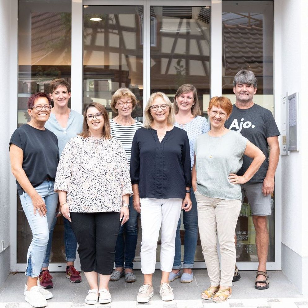 Eine Gruppe von Menschen posiert vor einer Glastür für ein Foto.