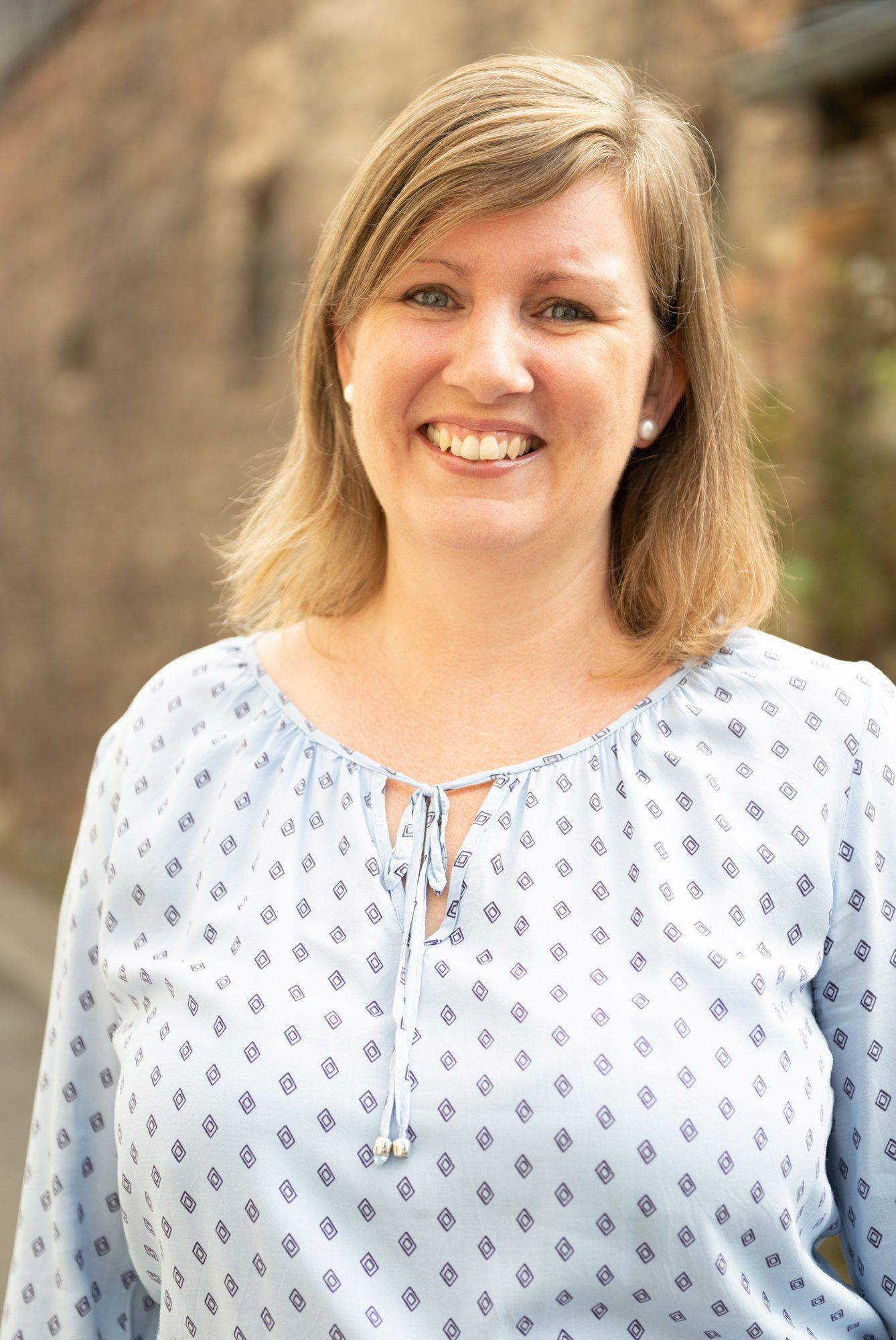 Eine Frau in einem blauen Hemd lächelt in die Kamera.