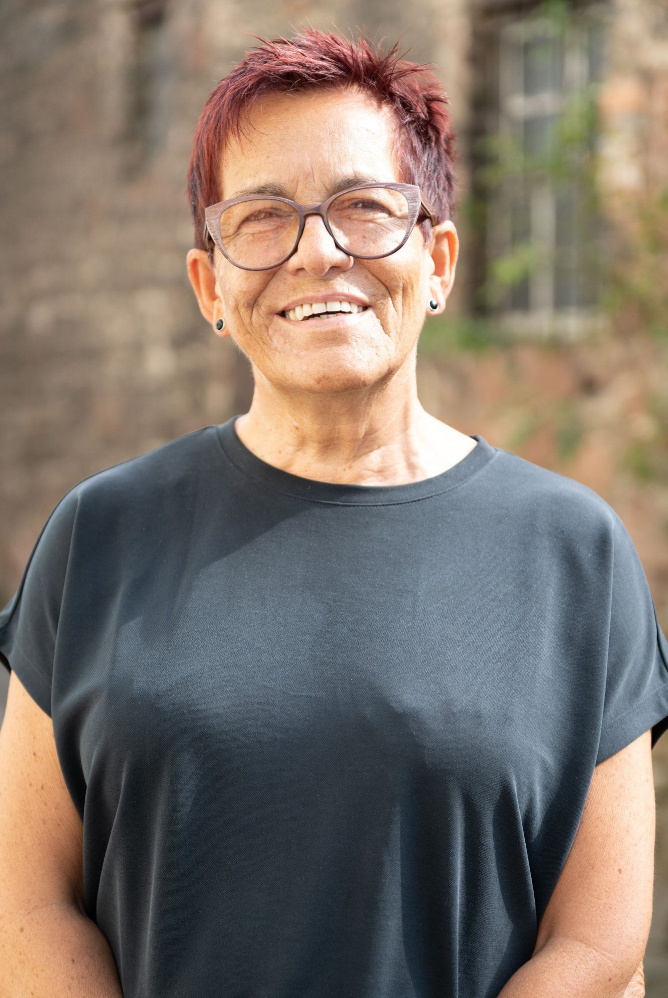 Eine Frau mit Brille und schwarzem Hemd lächelt in die Kamera.