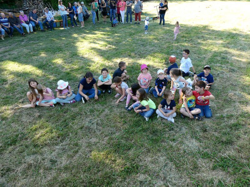 Eine Gruppe Kinder sitzt auf einer Wiese im Gras.