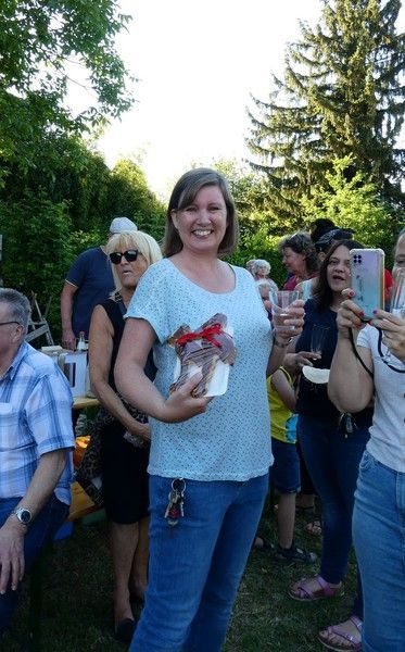 Eine Frau hält vor einer Menschenmenge eine Geschenkschachtel hoch.